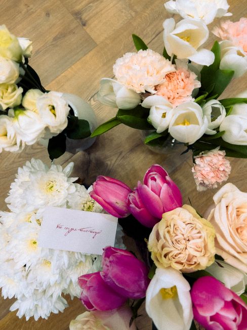 A collection of fresh floral arrangements featuring a variety of flowers such as white carnations, pink tulips, white calla lilies, peach roses, and white chrysanthemums, displayed on a wooden surface